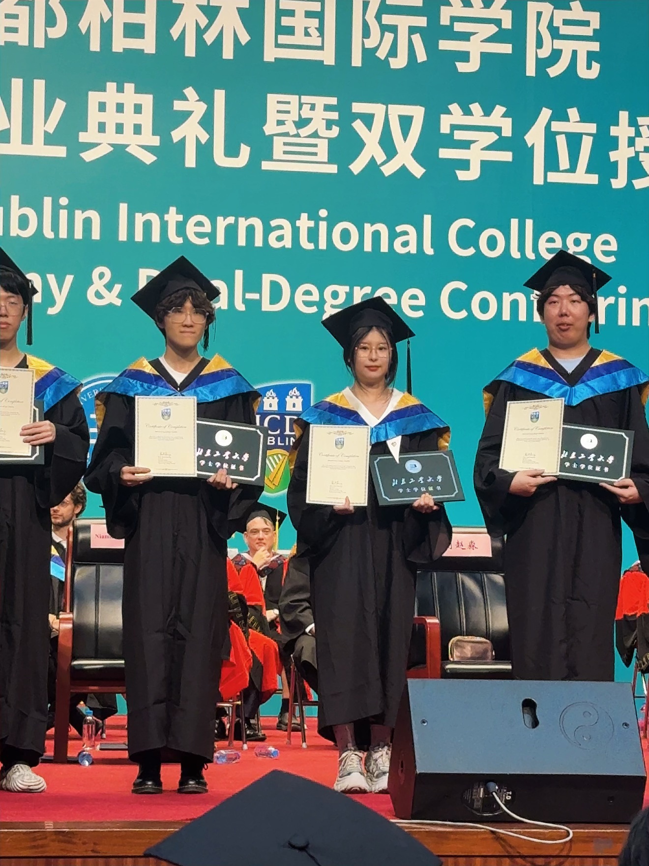 Shuhan at her UCD graduation ceremony holding her degree and awards